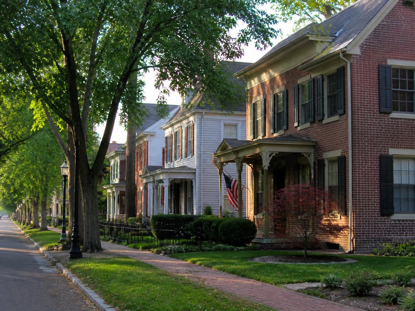 Tree-lined street of brick and clapboard homes with trimmed lawns in Wyoming, Ohio